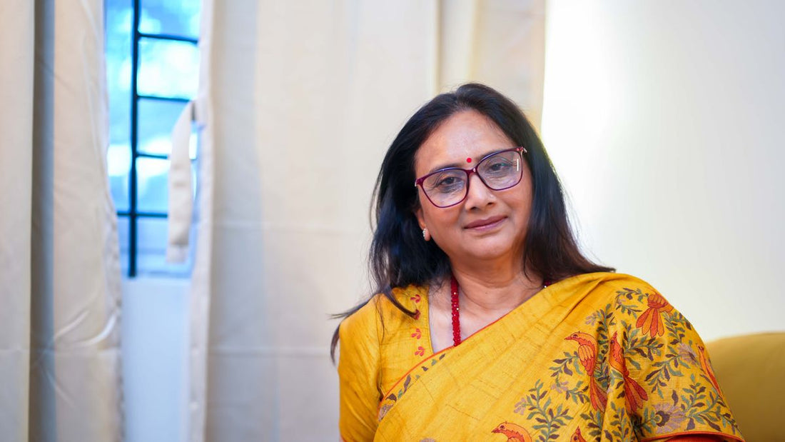 Smiling Indian woman in her late 40s wearing a yellow saree and glasses, confident about sex during menopause